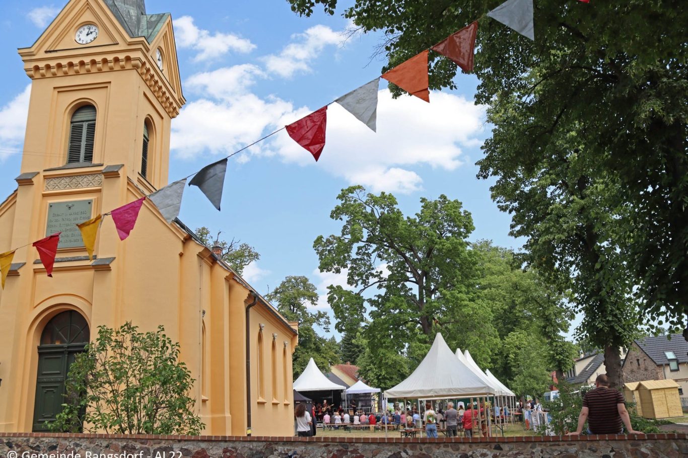 Rangsdorfer Kirche, festlich geschmückt, umgeben von Bäumen.